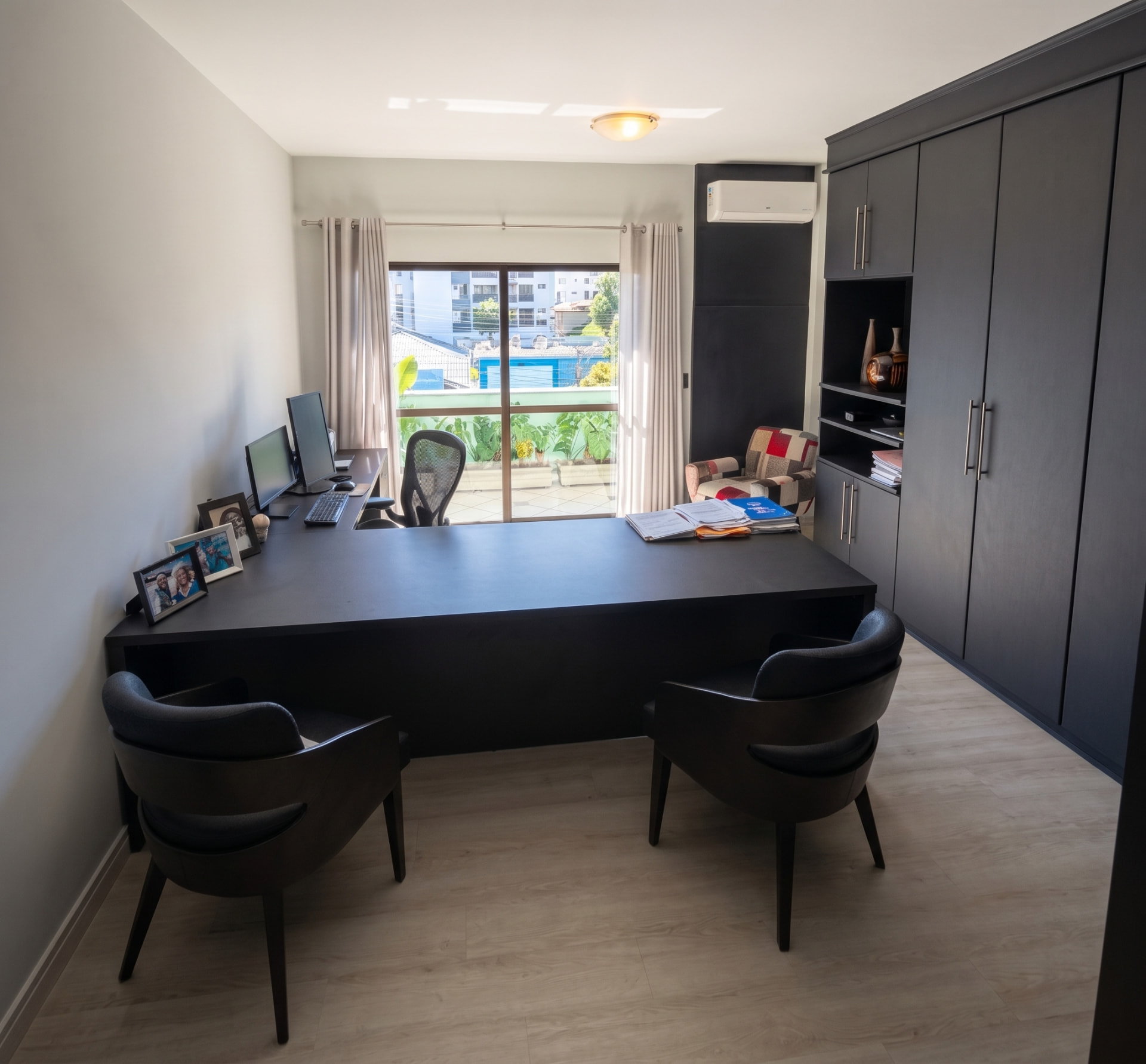 Sala de atendimento individual com mesa de trabalho, armários e cadeiras para clientes
